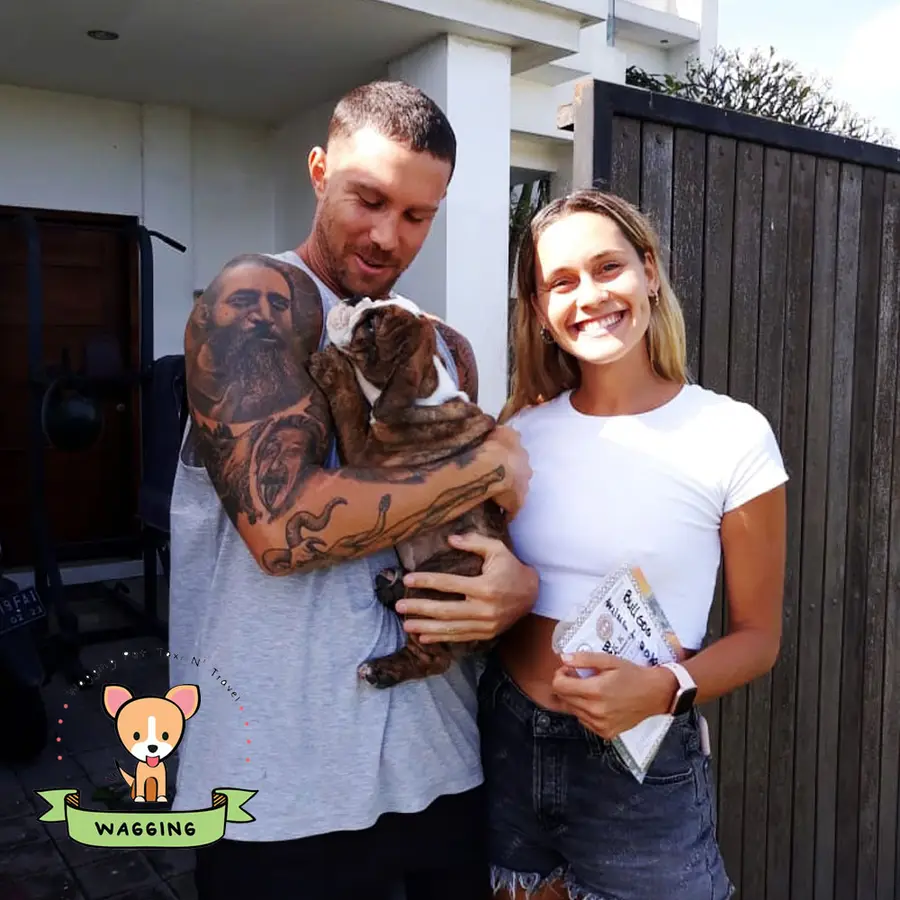 A couple holding their brown dog